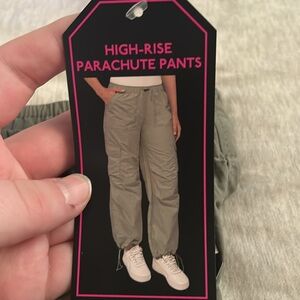 Army green parachute pants for camping. Adjustable closures at waist and ankles